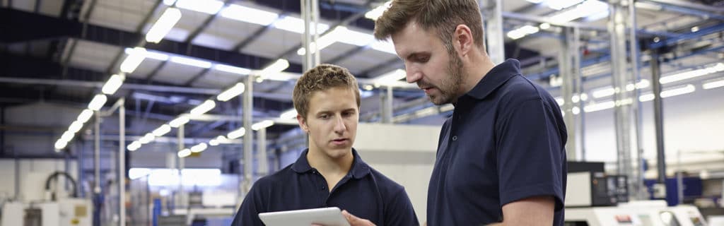 deux hommes dans une usine qui regardent une tablette tactile