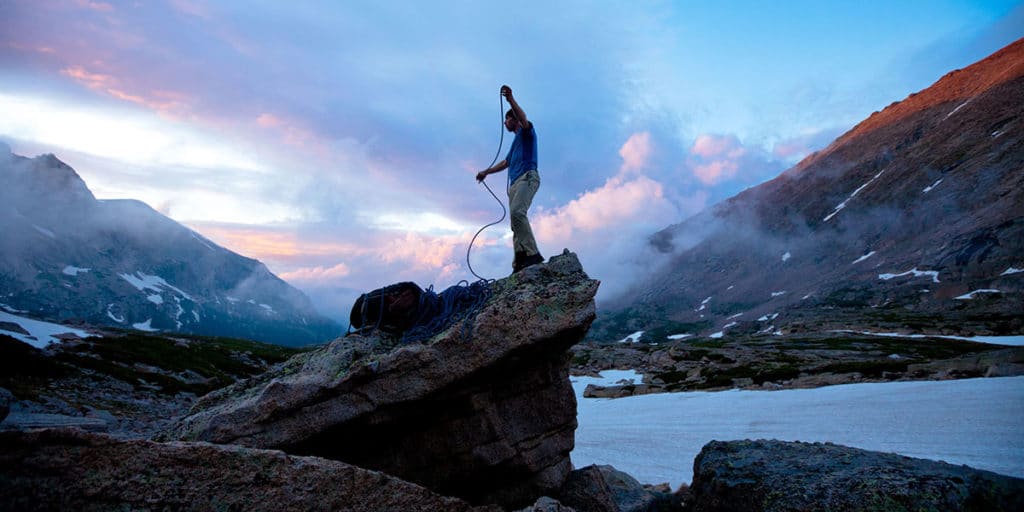 Alpiniste au coucher du soleil enroulant une corde