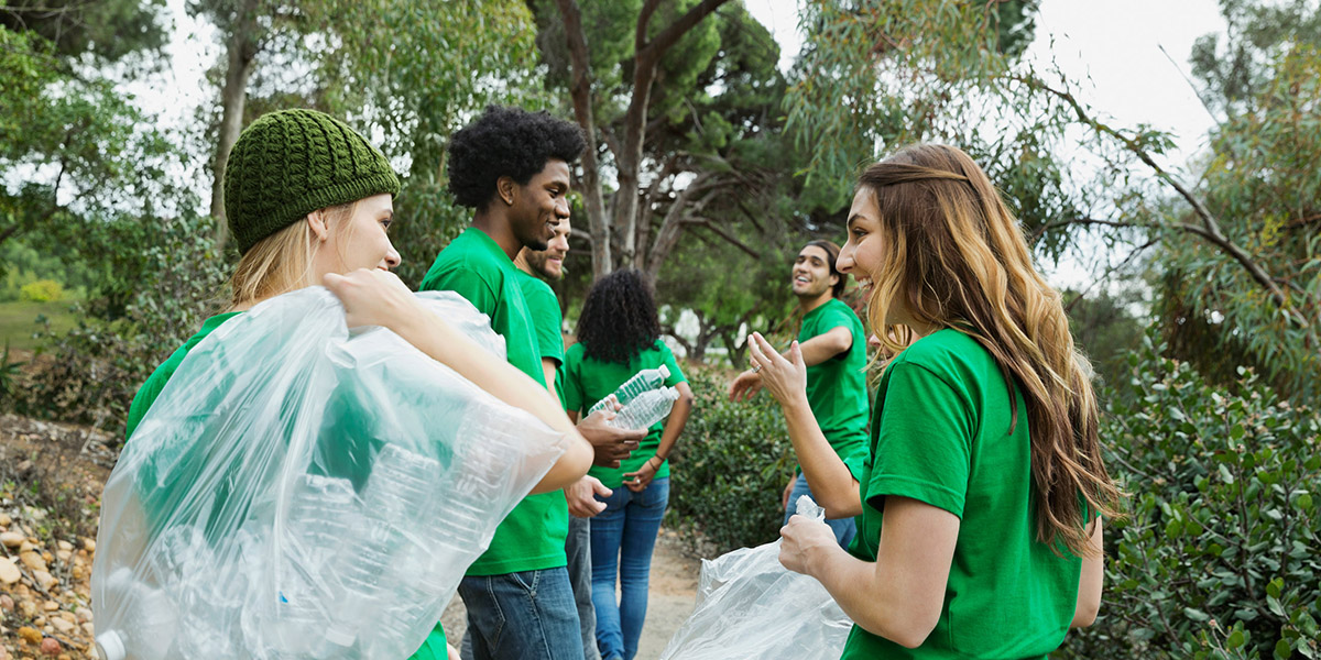 Equipe de jeunes bénévoles qui ramassent des déchets abandonnées dans la nature