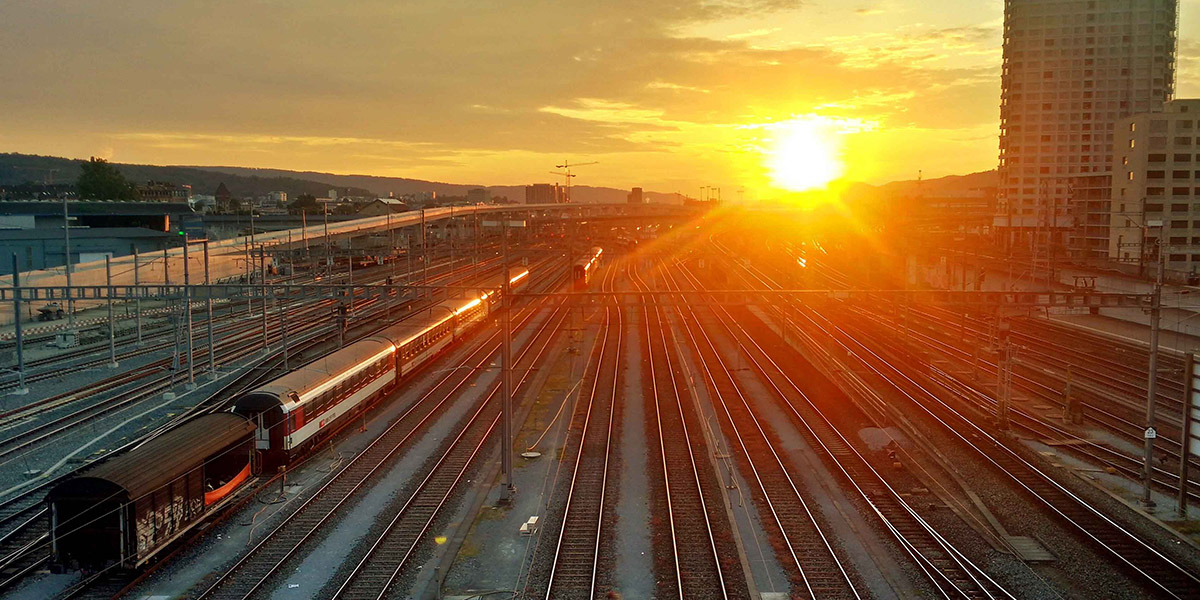 Photo d'un train sur un chemin de fer, avec un coucher de soleil en arrière plan