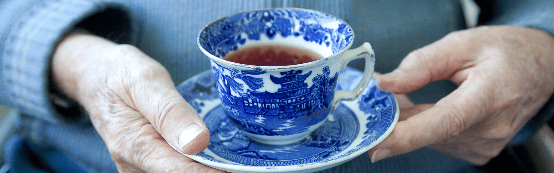Tasse de thé dans un service en porcelaine chinois tenue entre les mains d'un client