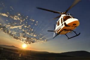 석양을 배경으로 날아가는 헬리콥터