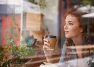 커피숍에서 책을 읽으며 커피를 마시는 젊은 여성
