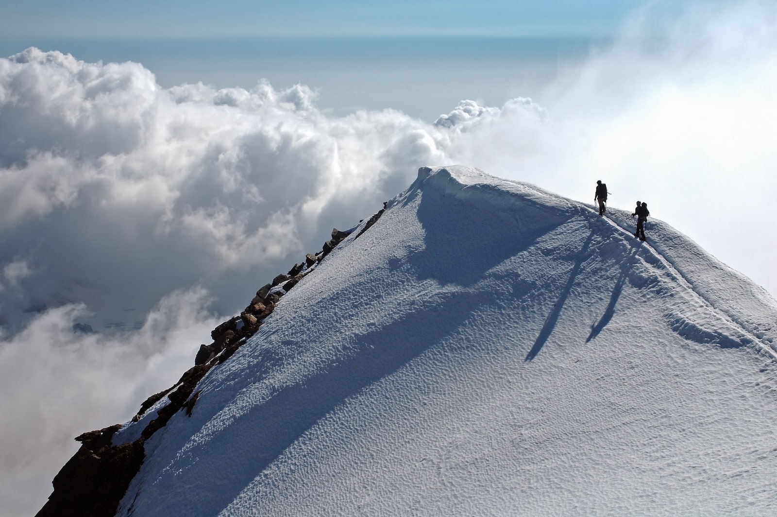 구름과 눈 덮인 산 정상을 걷는 두 등반객