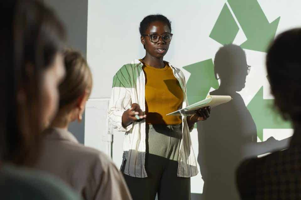 녹색 재활용 기호를 배경으로 발표하는 흑인 여성