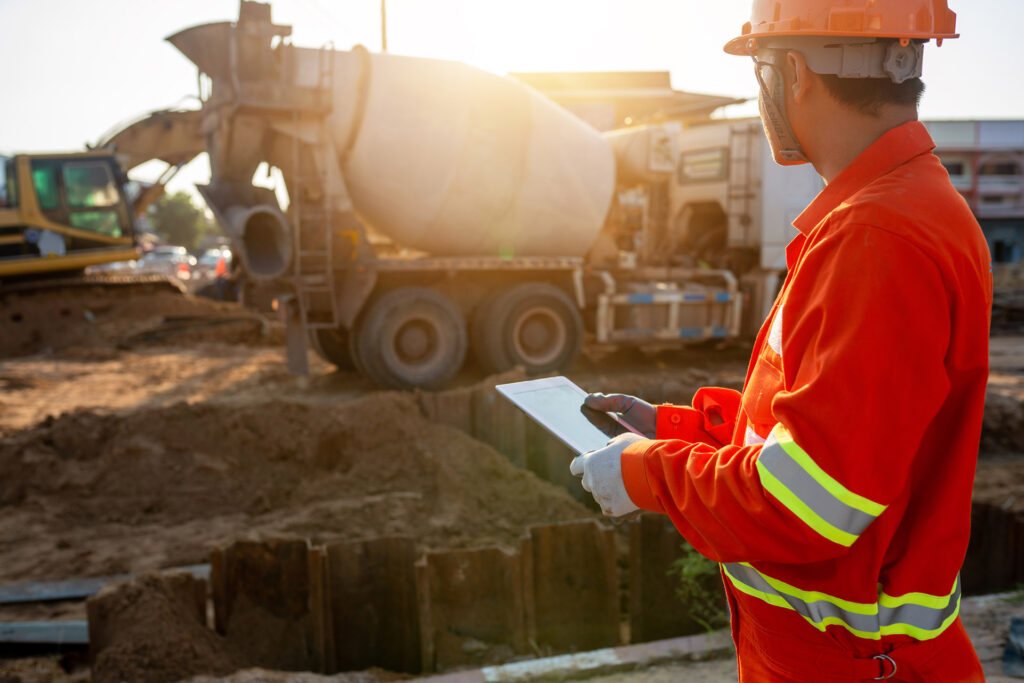 Engineer inspecting pouring of cement with tablet at an outdoor construction site