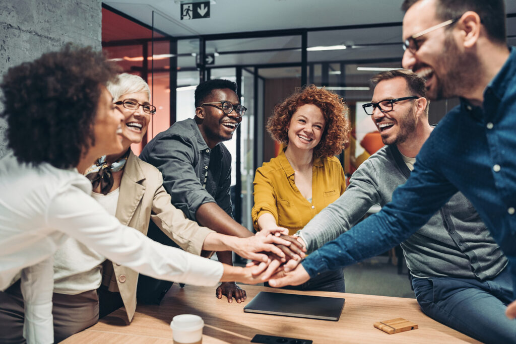 Smiling business persons stacking hands over the table