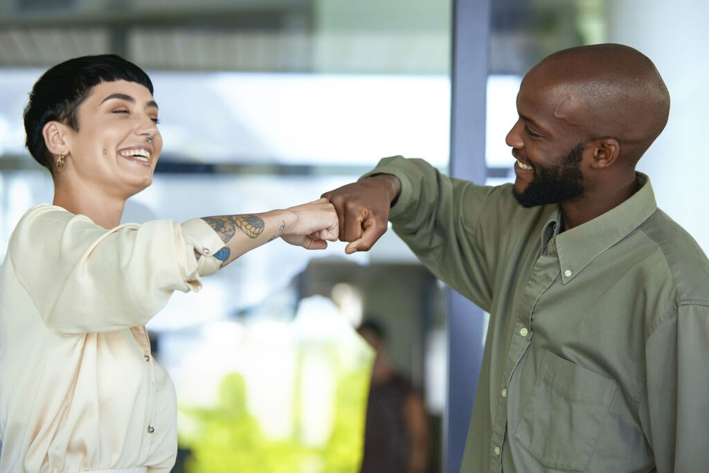 Two happy colleagues fist bumping