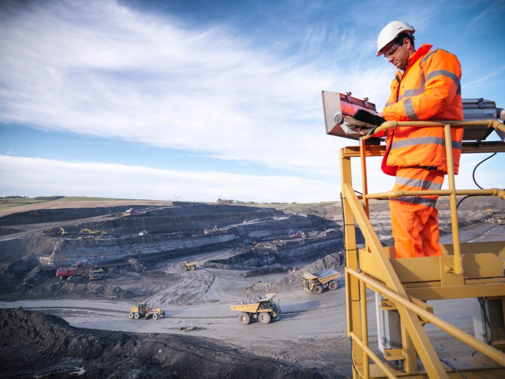 Ecologist using digital tablet surveying surface coal mine site from platform, elevated view --- Image by © Monty Rakusen/cultura/Corbis