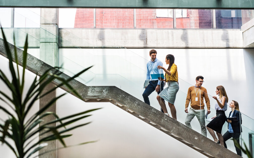 A group of businesspeople walking up the stairs in the modern building, talking.