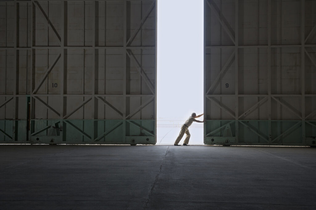 Worker opening large warehouse doors