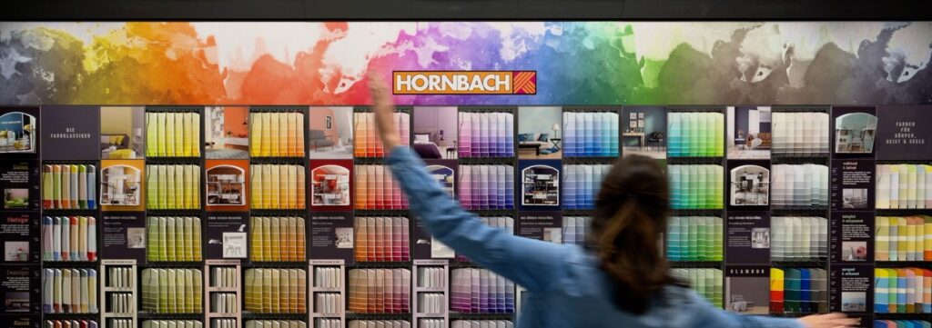 Customer in front of a Hornbach paint shelf in the shop.