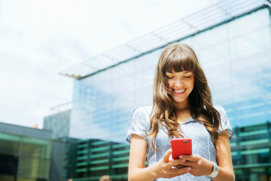 Woman using smart phone with offices in background