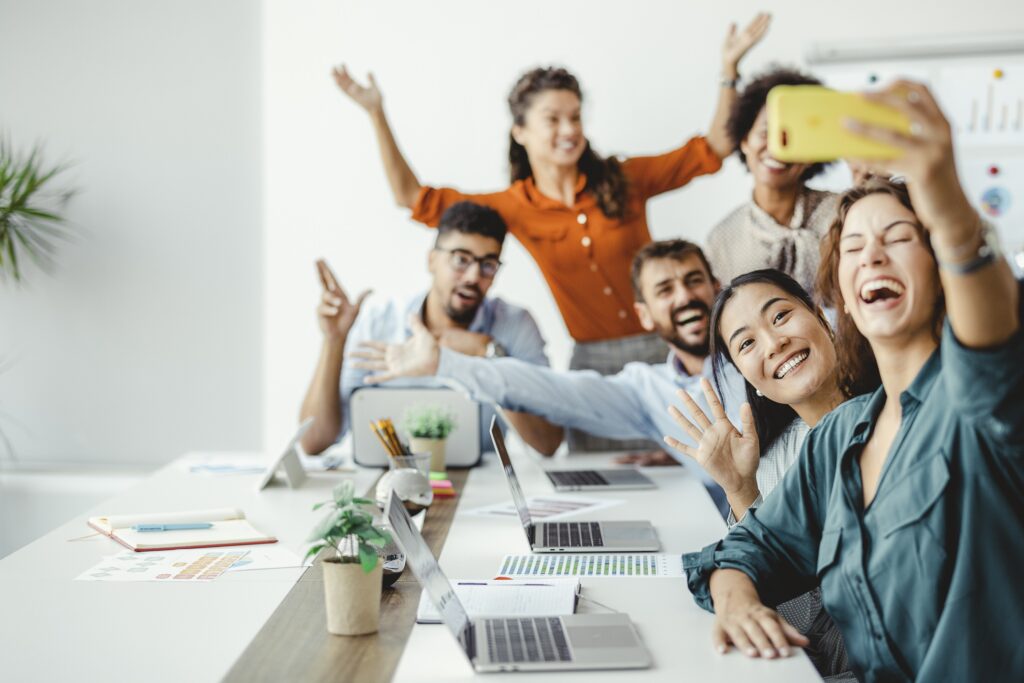 Group of multiracial businesspeople taking selfies with smartphone during break in office.