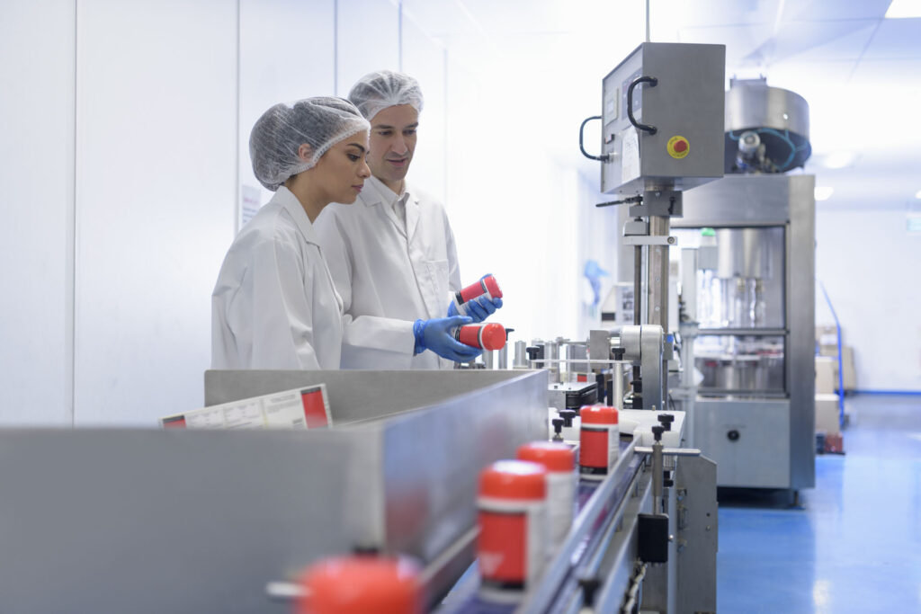 Workers on pill packing line in pharmaceutical factory