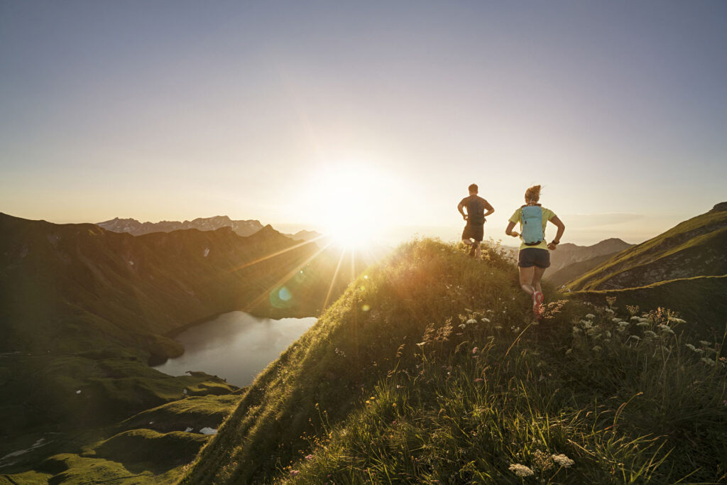 Two people running on a mountain trail