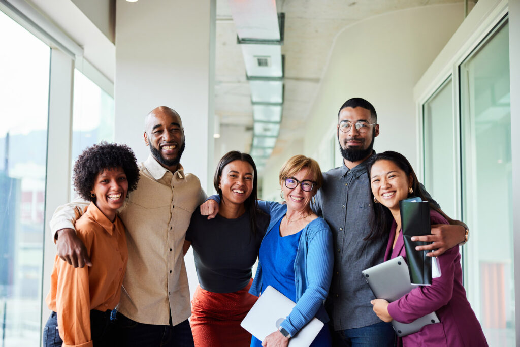 Smiling businesspeople standing arm in arm in an office hall