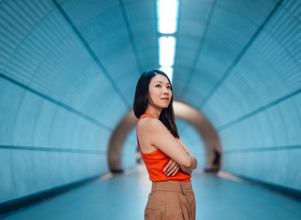 Portrait of young Asian woman with arms crossed standing in a futuristic tunnel