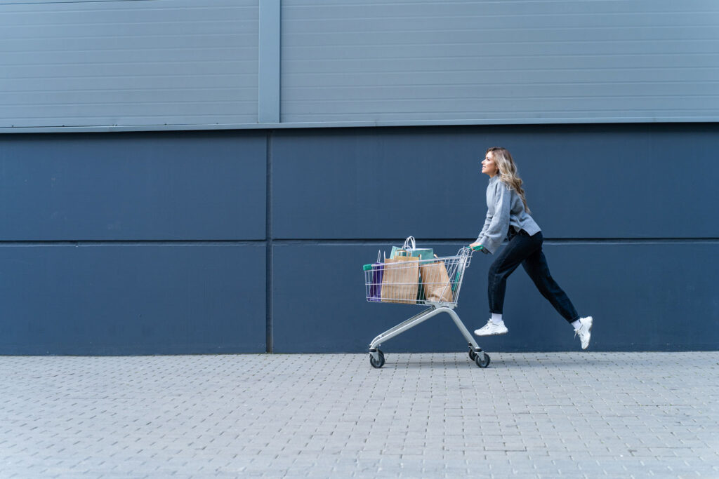 Woman jumping as she pushes shopping cart