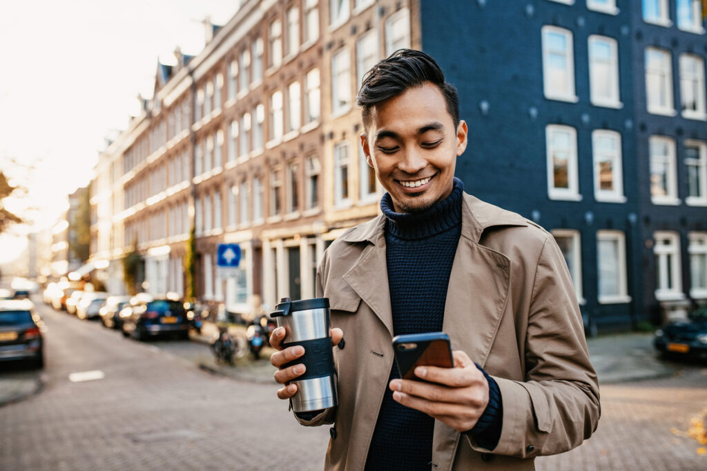 Businessperson using smart phone and drinking coffee from reusable cup